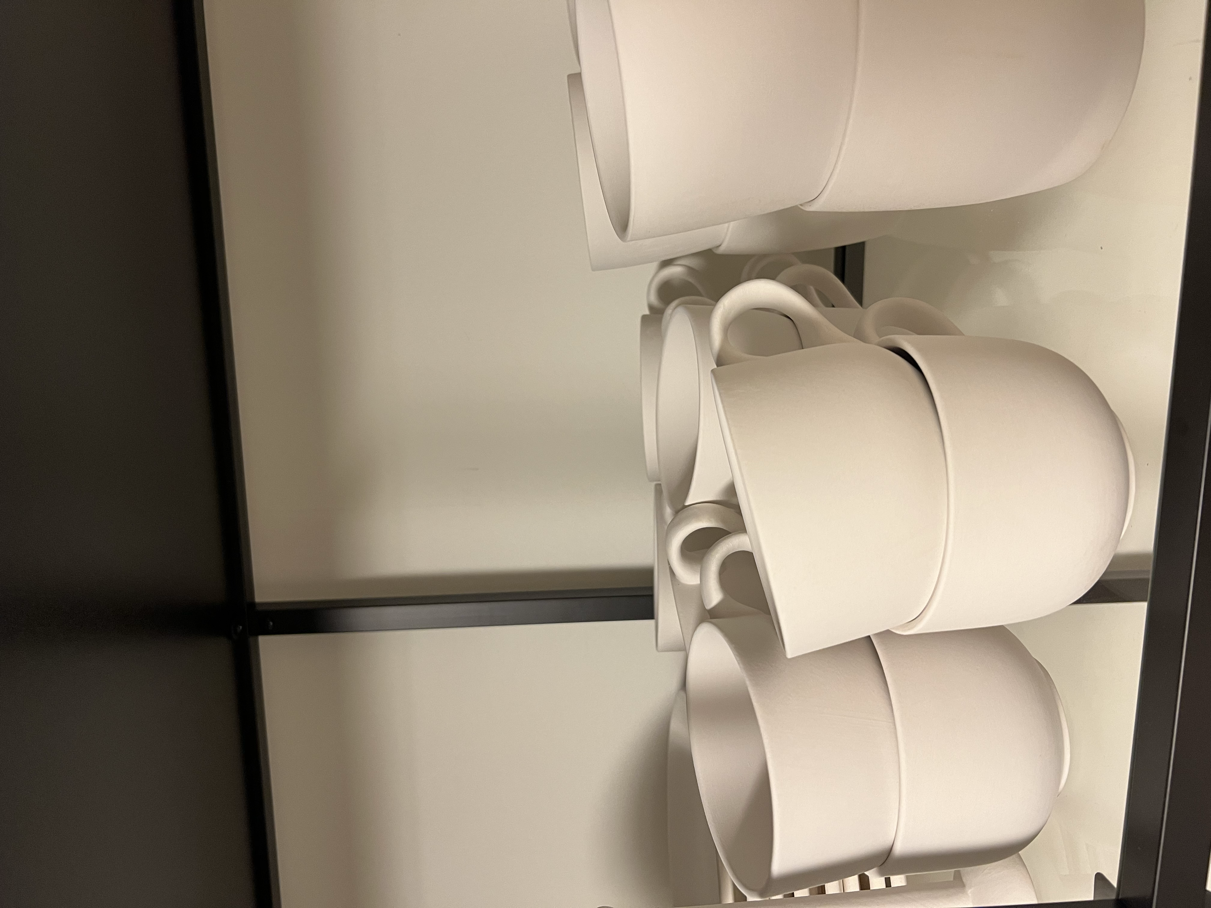 Flere personer maler keramikk sammen rundt et langt trebord med fargekopper og kaffekopper